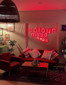 Pink "Colour mood magic" LED neon sign above a sofa in a lounge