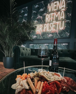 LED neon sign "Viena ritmā ar pilsētu" on flamingo wallpaper in a wine bar