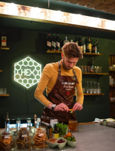 White hexagon "HEX" LED neon logo sign behind a cocktail bar