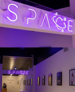 Purple "Space" LED neon logo sign in an office corridor