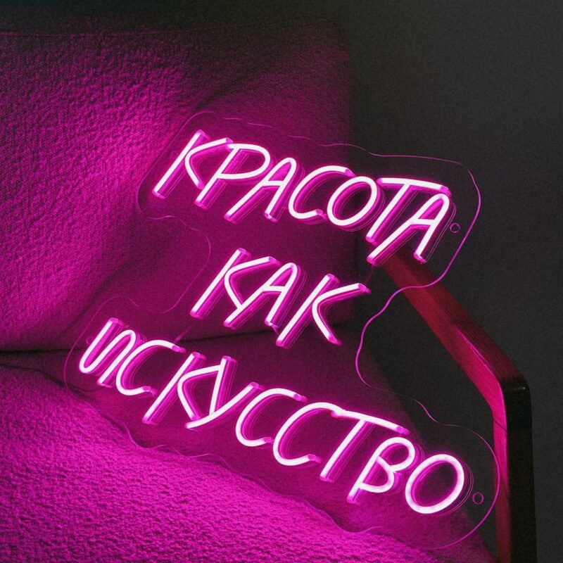 Pink neon quote sign meaning “Beauty as art” on a pink chair