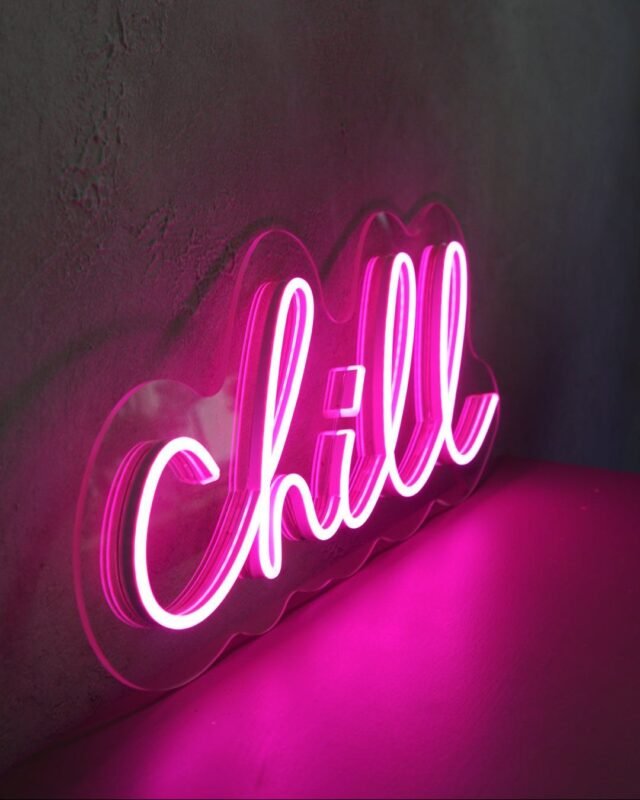 Pink “Chill” LED neon sign glowing on a sofa