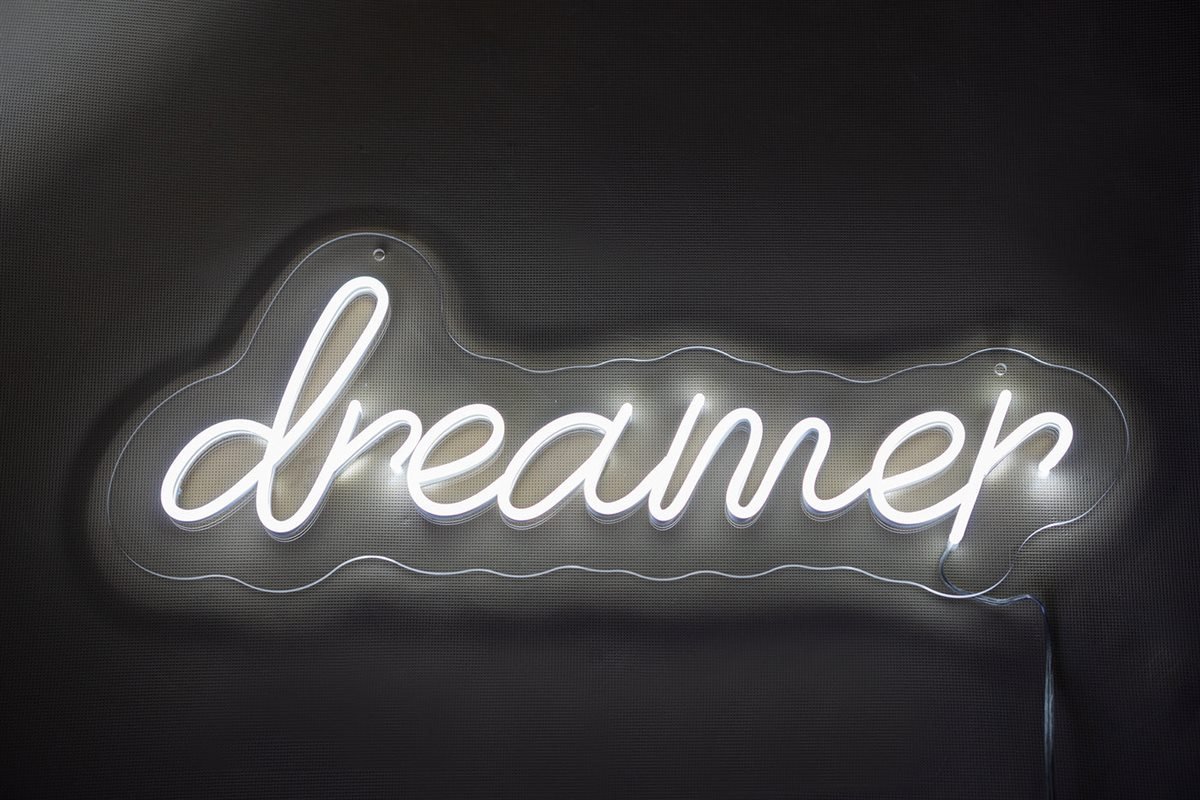 White “Dreamer” script LED neon sign on a dark bedroom wall