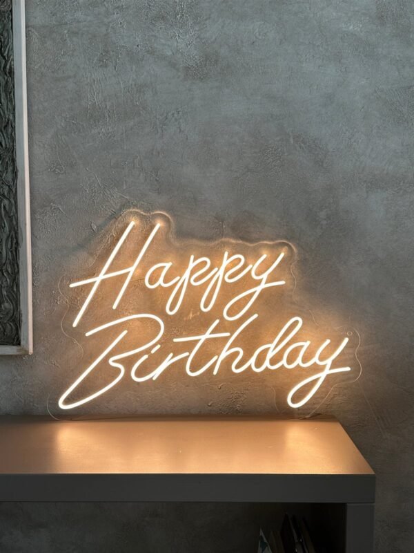 Warm white Happy Birthday LED neon sign on a grey wall