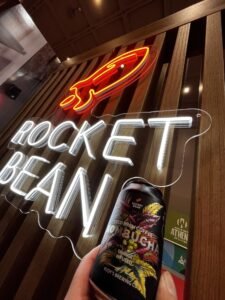 Red rocket and white "Rocket Bean" LED neon logo sign in a coffee shop